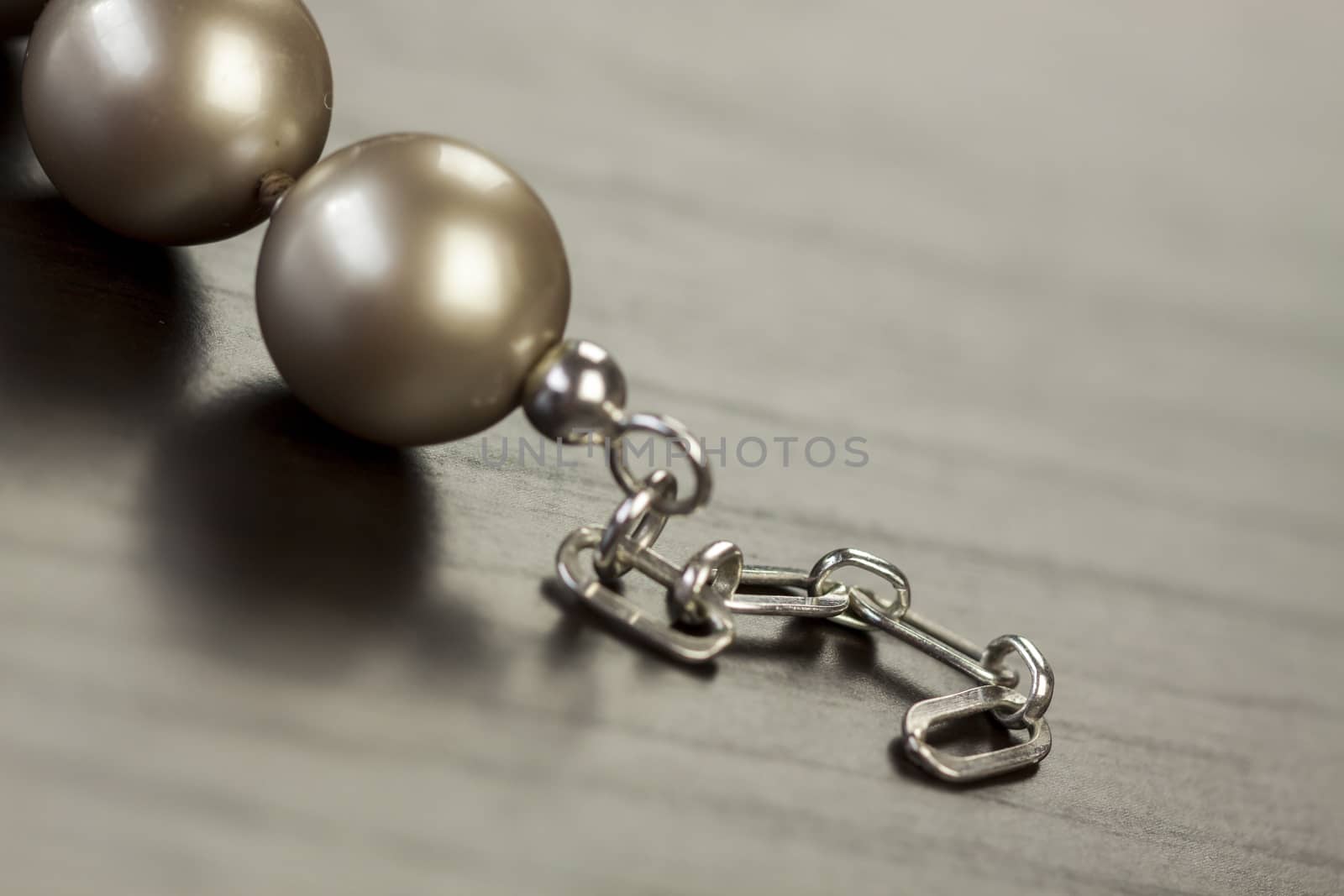 String of shiny grey beads winding through the frame in a close up view of fashion jewellery with selective focus to two beads
