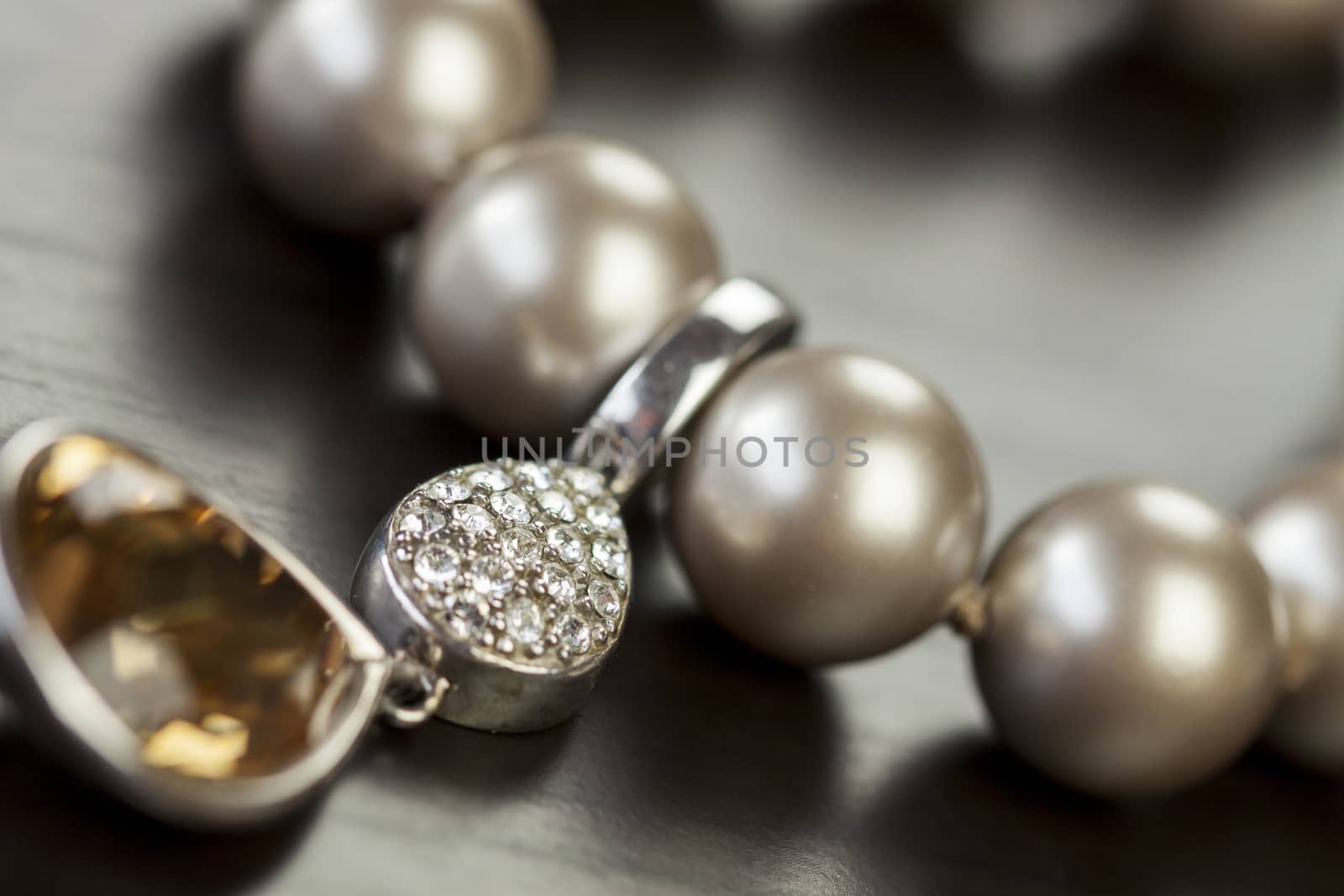 String of shiny grey beads winding through the frame in a close up view of fashion jewellery with selective focus to two beads