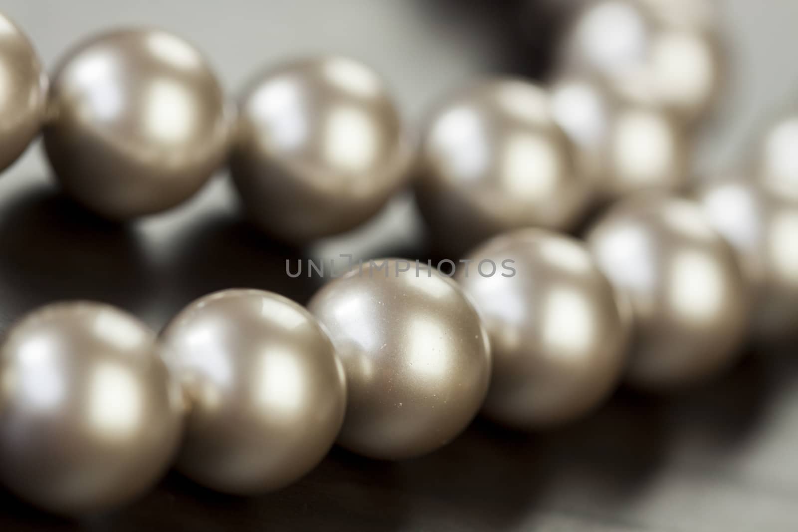 String of shiny grey beads winding through the frame in a close up view of fashion jewellery with selective focus to two beads