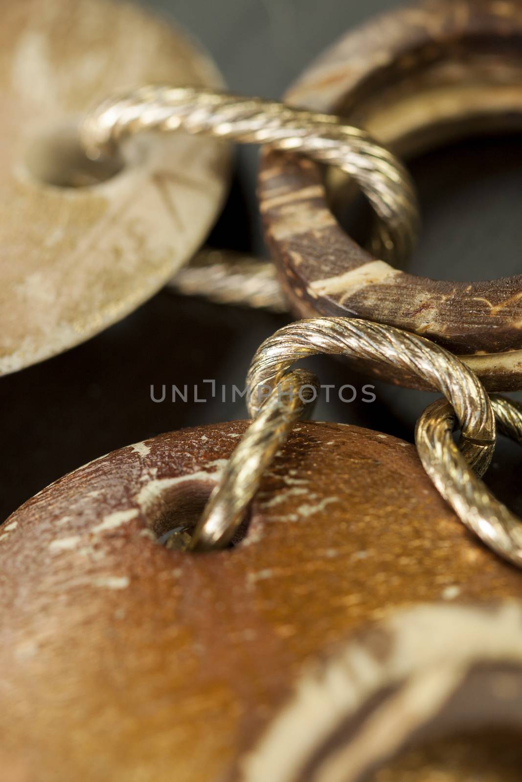 Scratched and tarnished old silver jewellery with two flat discs flanking a ring suspended on an oval link chain, close up view on a grey background