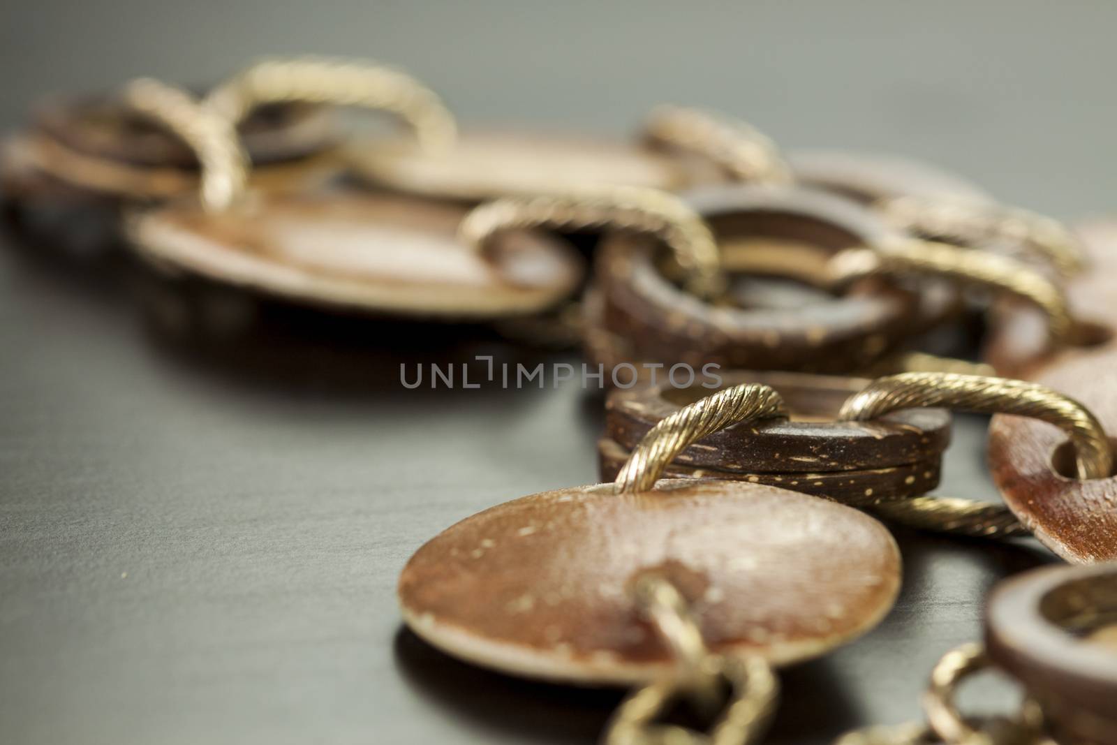 Scratched and tarnished old silver jewellery with two flat discs flanking a ring suspended on an oval link chain, close up view on a grey background