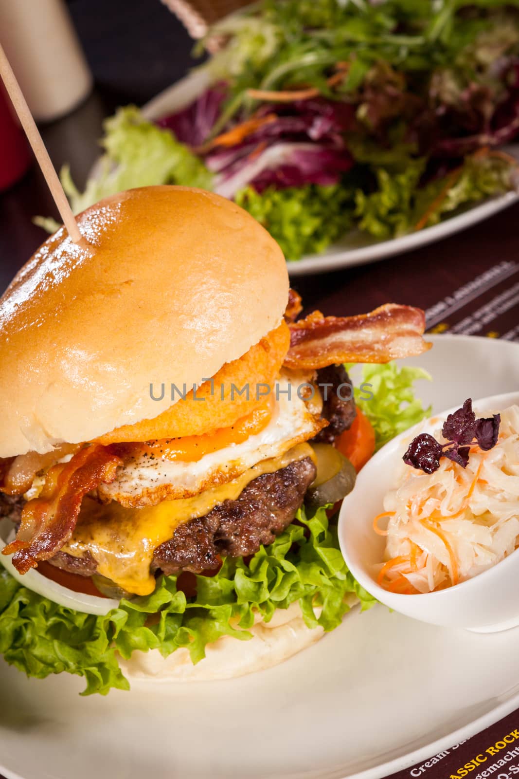 Delicious egg and bacon cheeseburger with a nutritional filling of salad ingredients, a ground beef patty, cheese, fried egg and crispy bacon on a white crusty roll