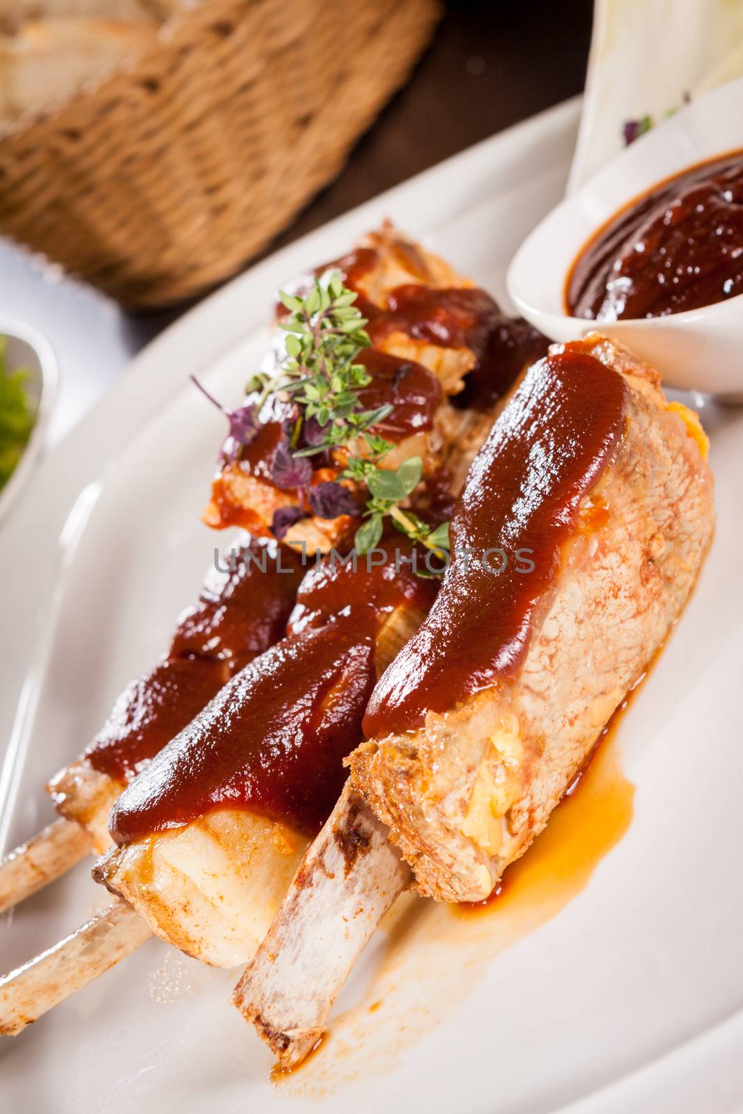 Delicious grilled pork ribs served with a rich brown gravy or BBQ sauce garnished with fresh herbs , close up side view