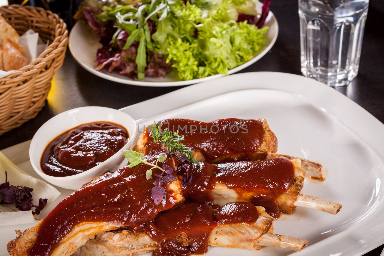 Delicious grilled pork ribs served with a rich brown gravy or BBQ sauce garnished with fresh herbs , close up side view