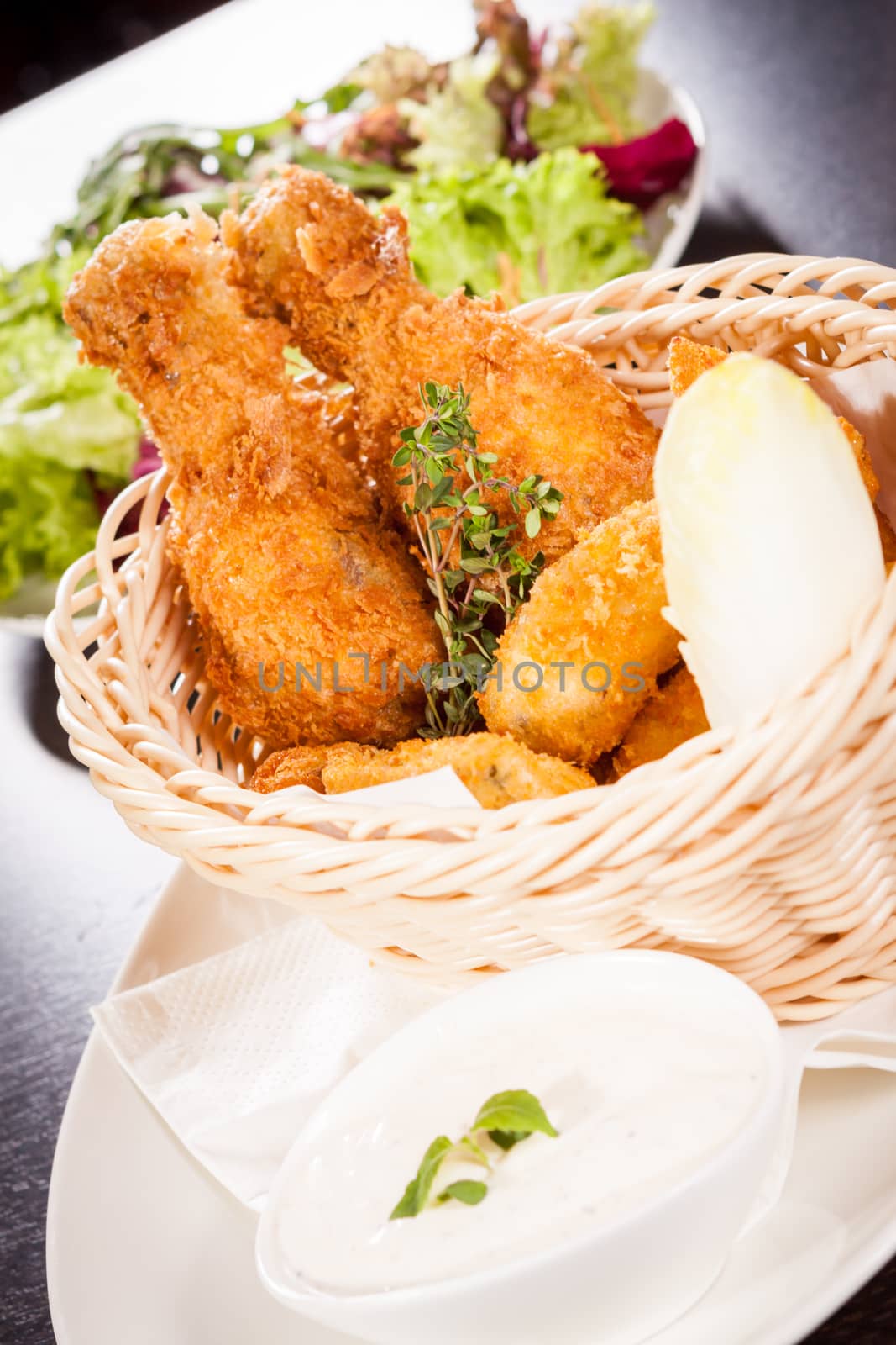 Crisp crunchy golden chicken legs and wings deep fried in bread crumbs and served with a bowl of dip in a wicker basket for a delicious appetizer