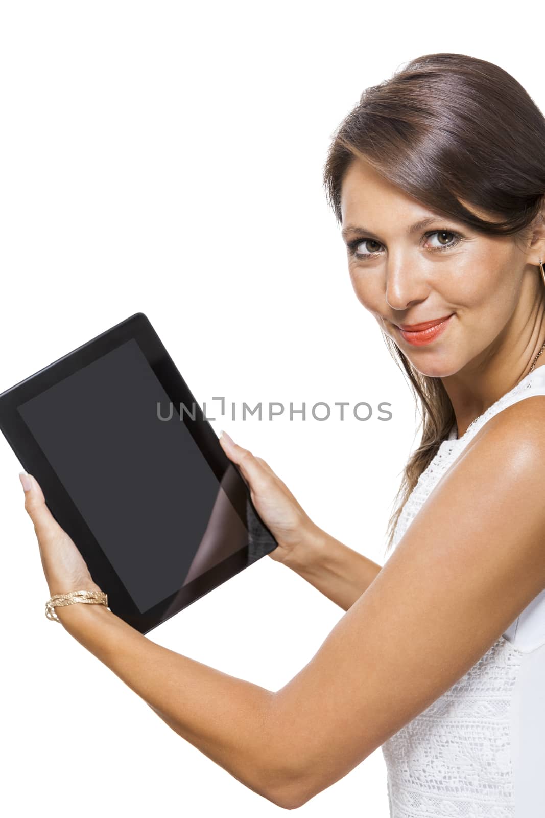 Attractive young business woman standing chatting on a mobile while simultaneously reading a tablet computer with a smile, isolated on white