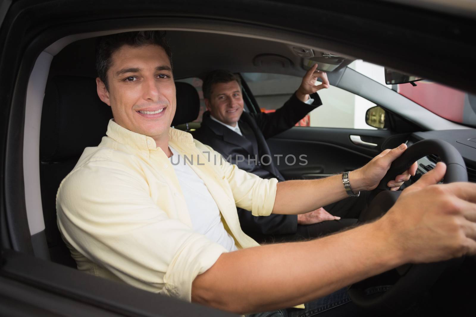 Businessman pointing a car interior at new car showroom