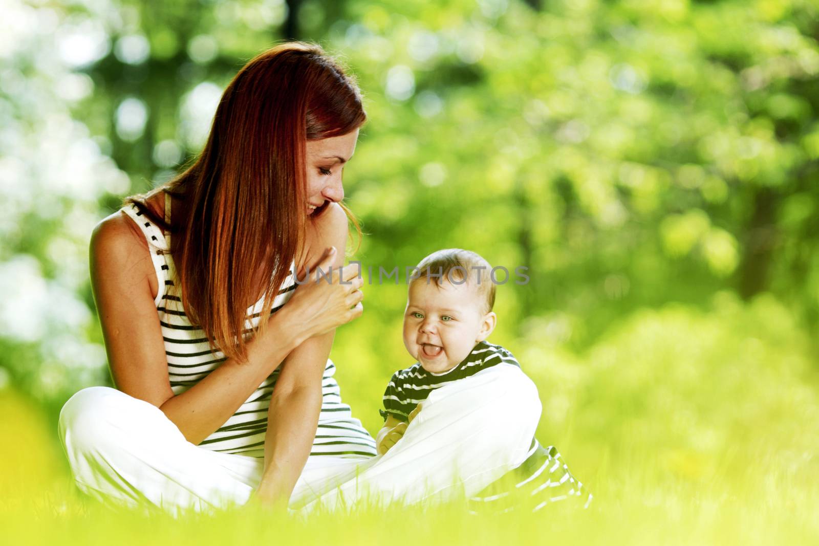 Mother and daughter sitting on grass in spring park