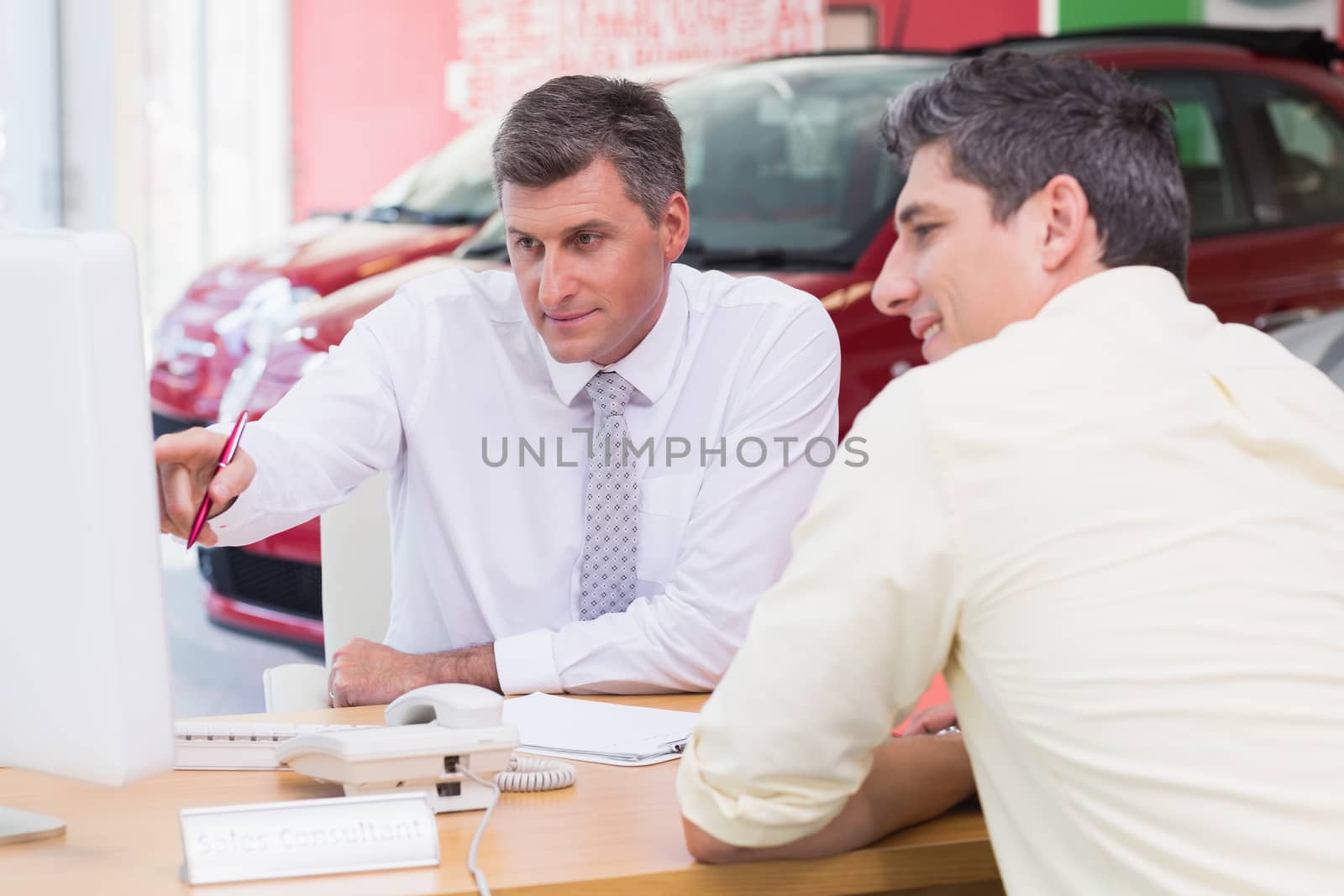 Businessman pointing his finger at screen at new car showroom