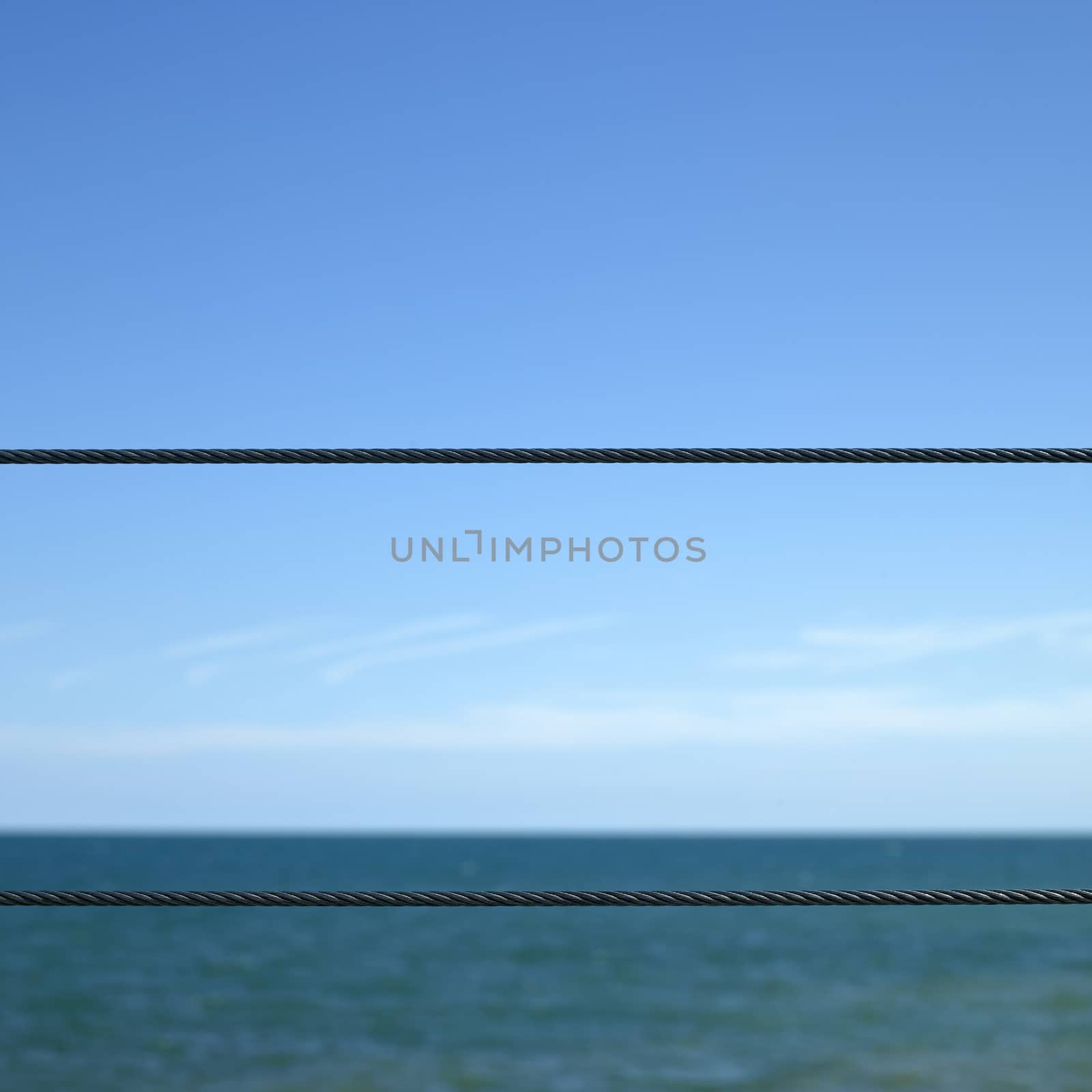 Blue ocean viewed from a metal wired fence