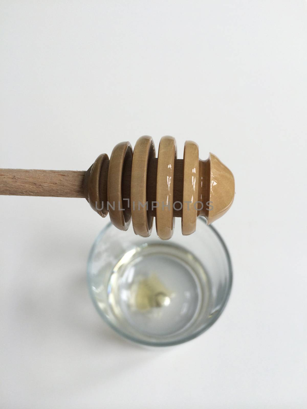 Used honey dipper dripping in glass