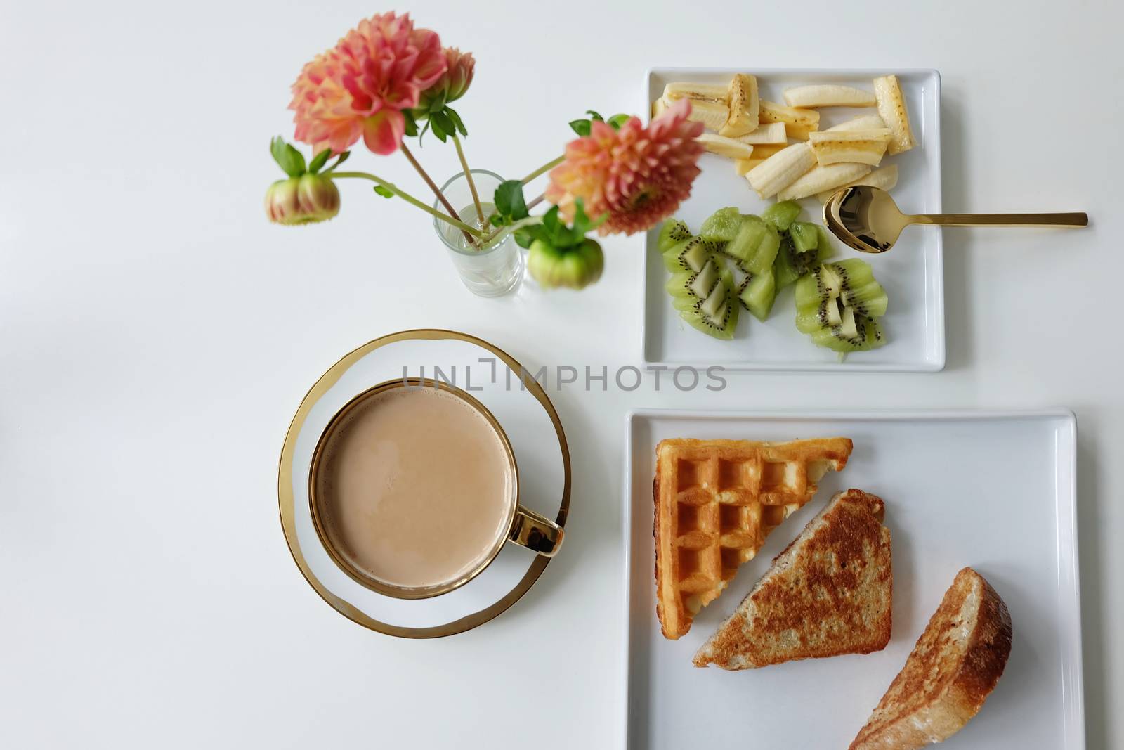 Waffles, Frech toast, Fruit and latte with flowers and gold spoon on white table ware