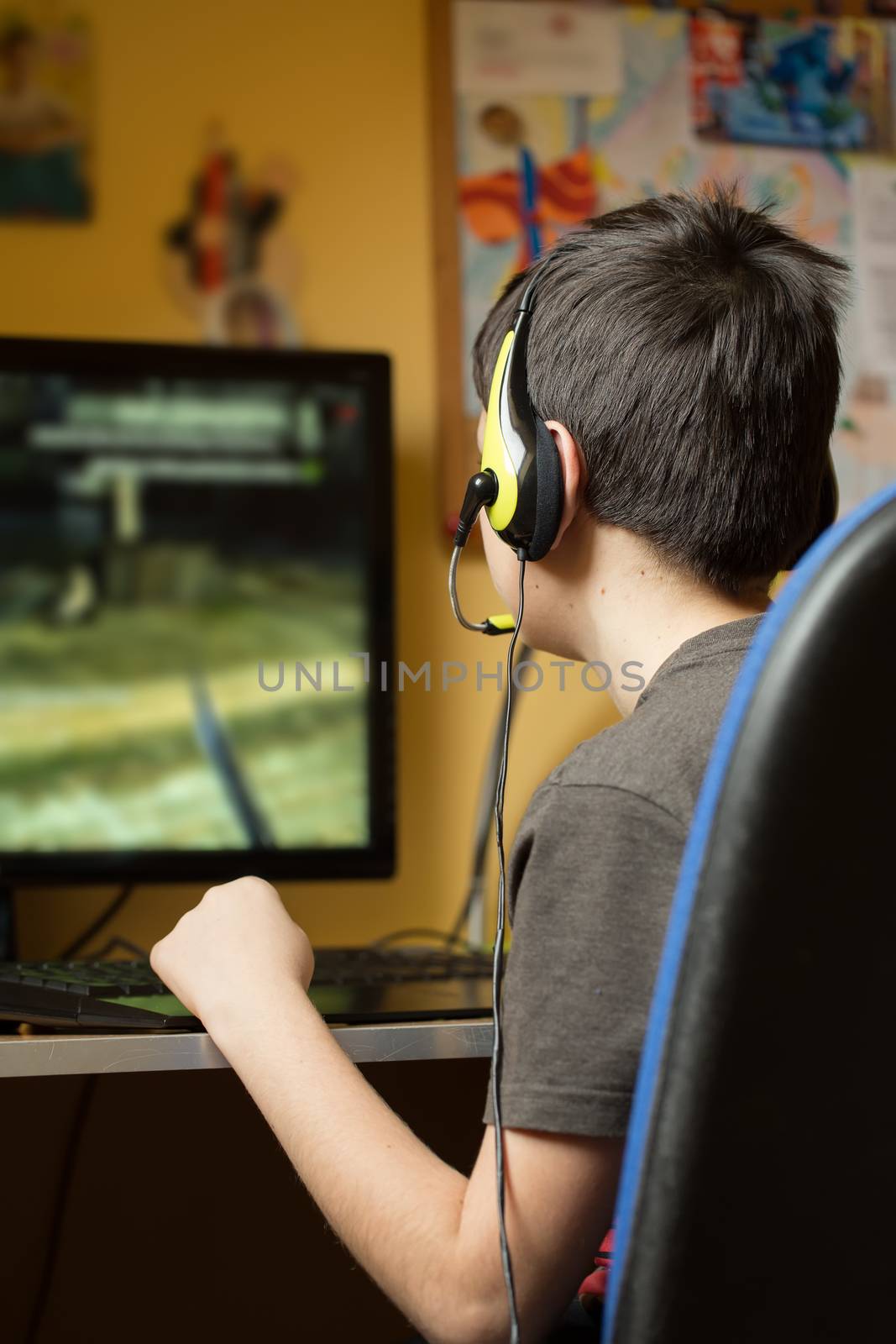 Boy using computer at home, playing game by artush