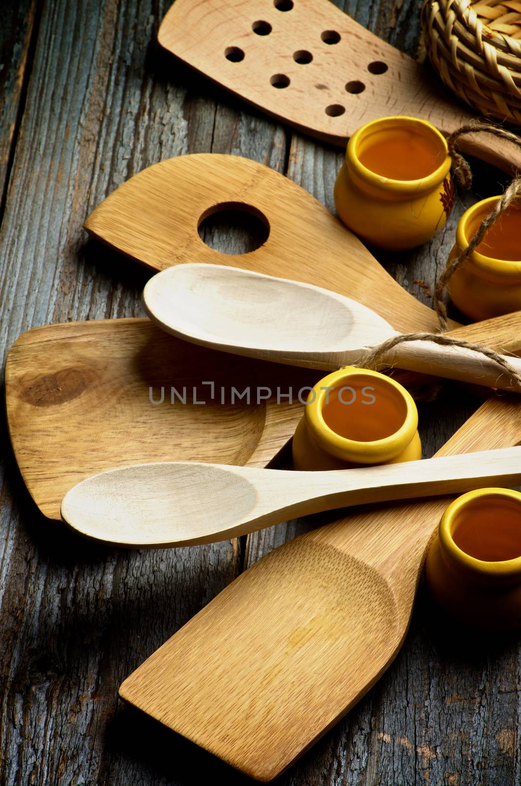 Arrangement of Kitchen Utensils with Wooden Spoons, Spatula and Small Pots closeup on Rustic Wooden background