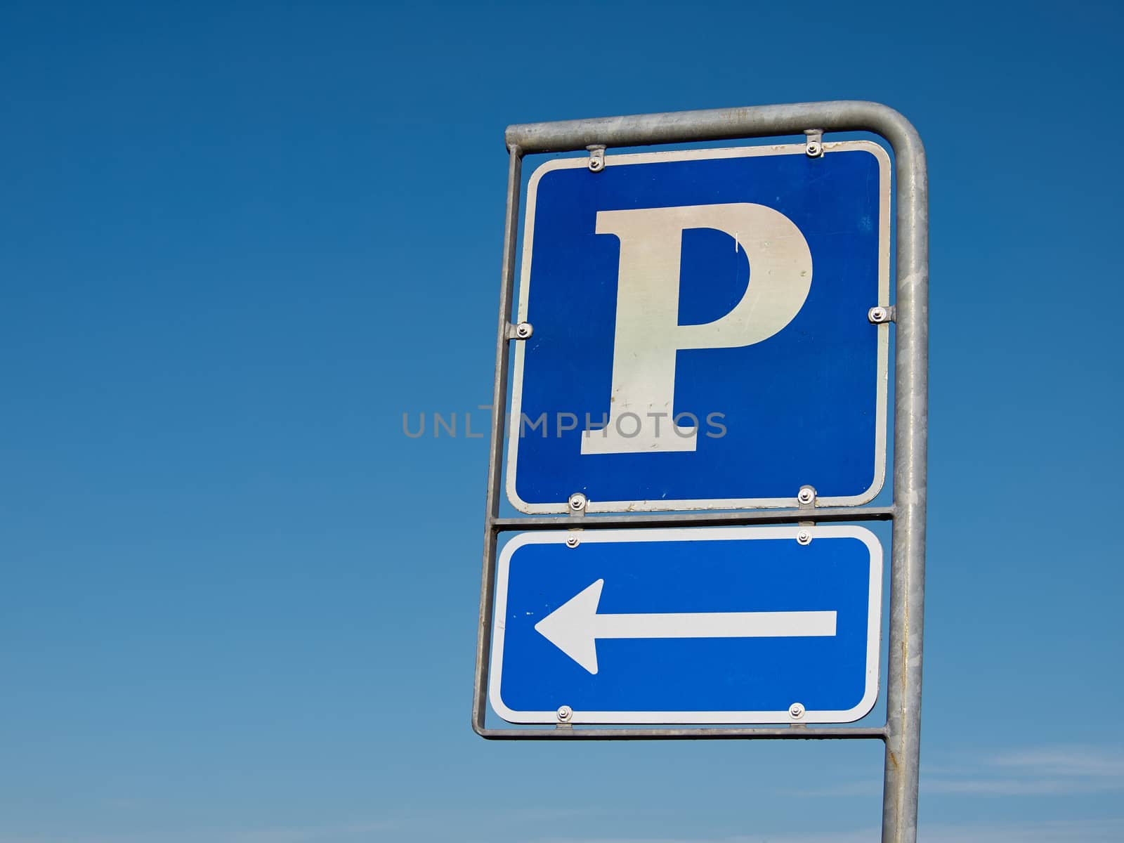 Parking symbol sign with direction arrow with clear blue sky background