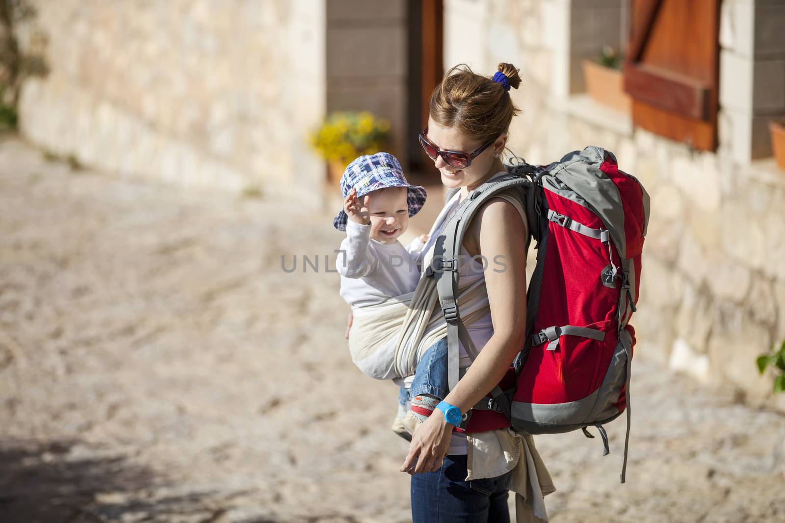 Woman tourist carrying her little son in sling by photobac