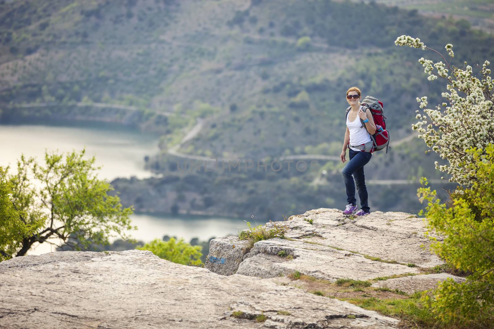 Woman traveller standing on cliff and smiling by photobac