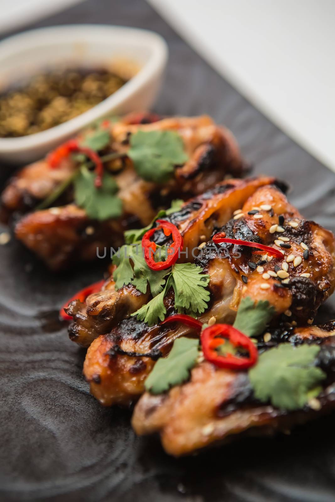 Hot organic chicken wings with red pepper on black dish