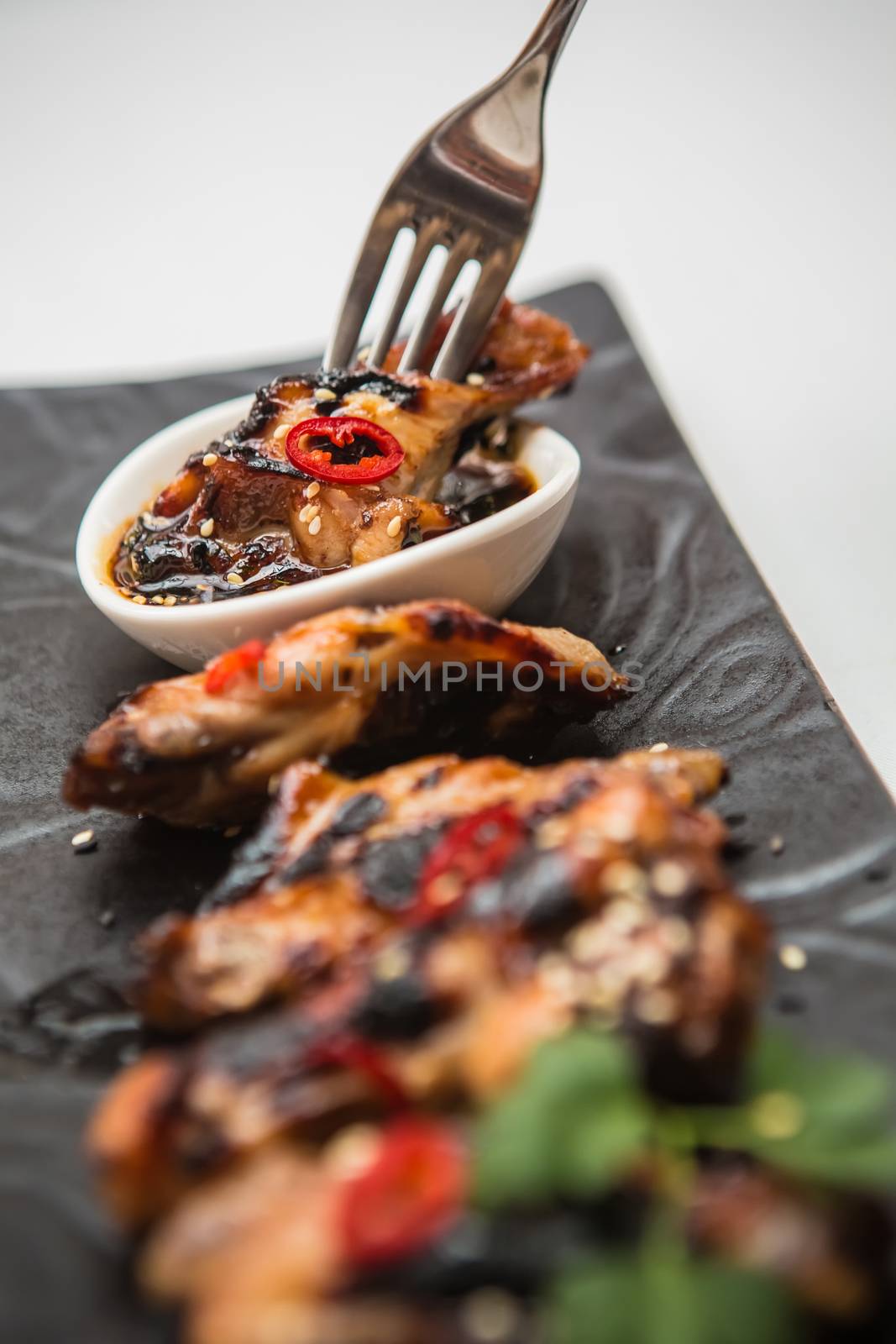 Hot organic chicken wings with red pepper on black dish