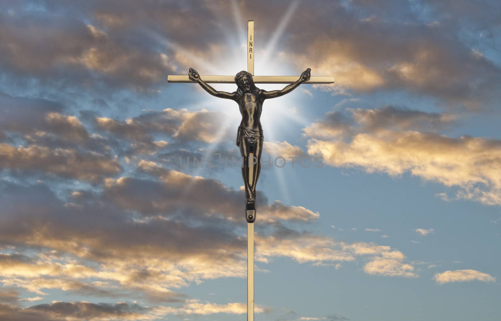 Jesus Christ passion on the cross back lit by sunset