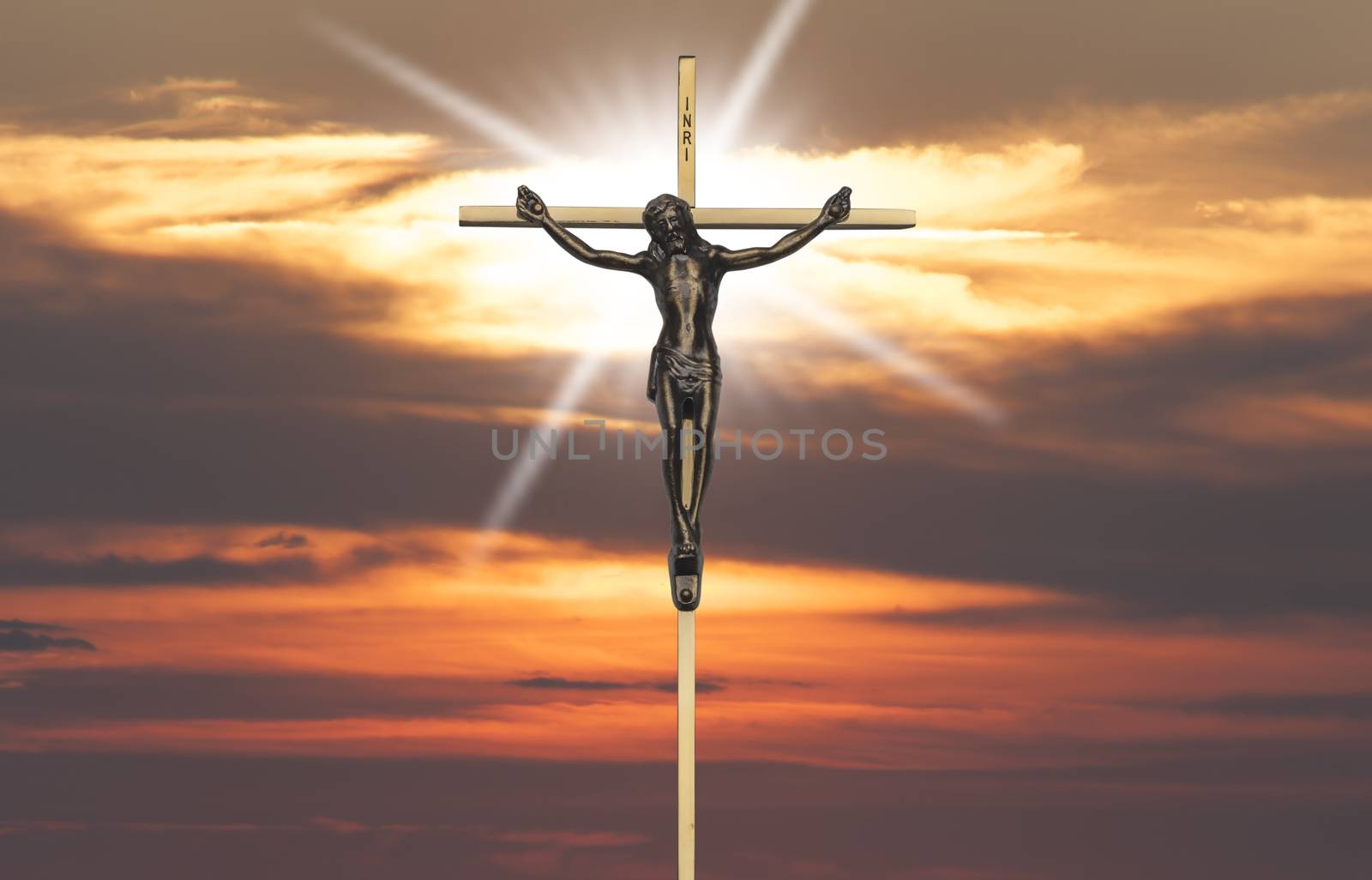 Jesus Christ passion on the cross back lit by sunset