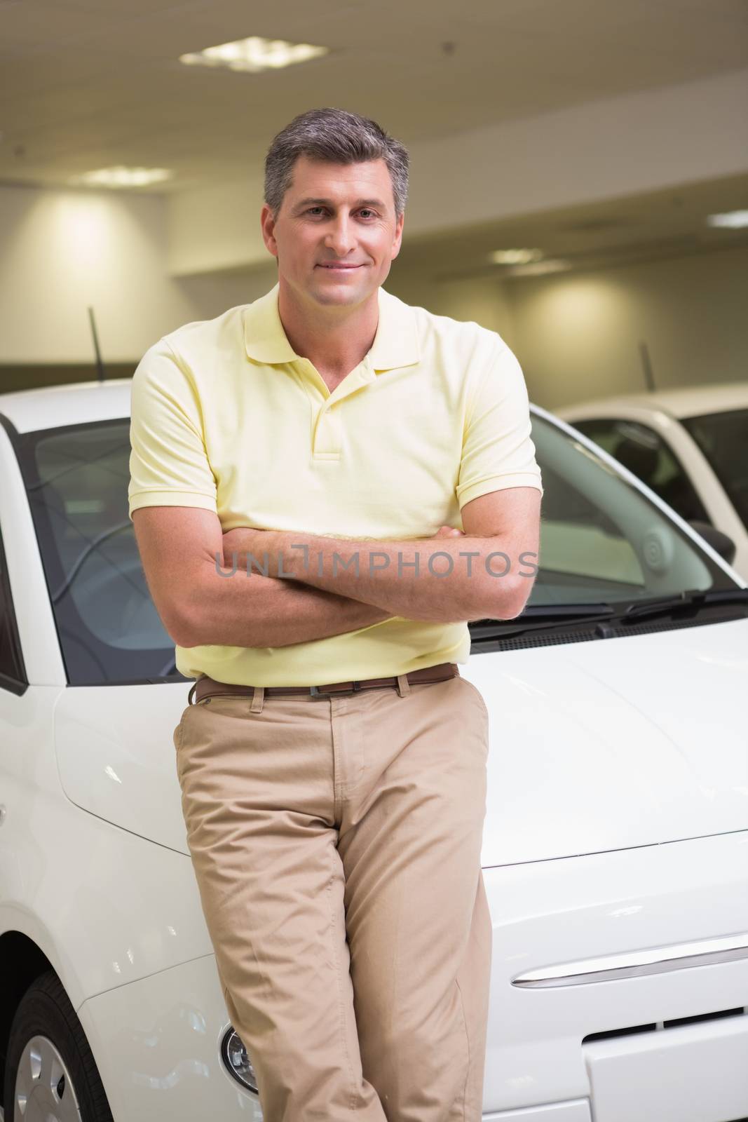Smiling customer leaning on car with arms crossed by Wavebreakmedia