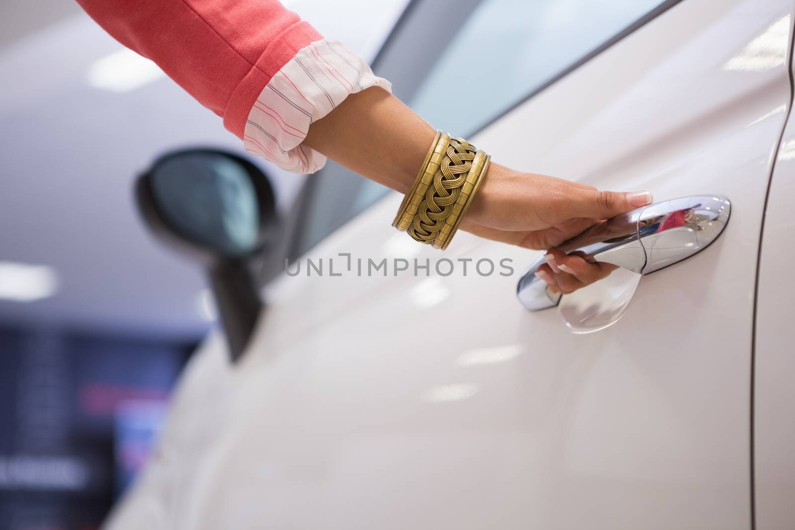Woman holding a car door handles at new car showroom