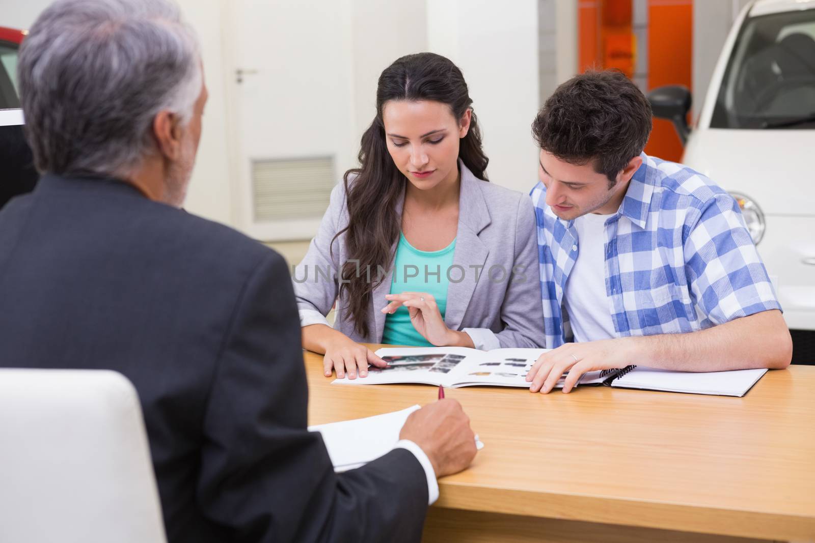 Smiling couple reading a booklet at new car showroom