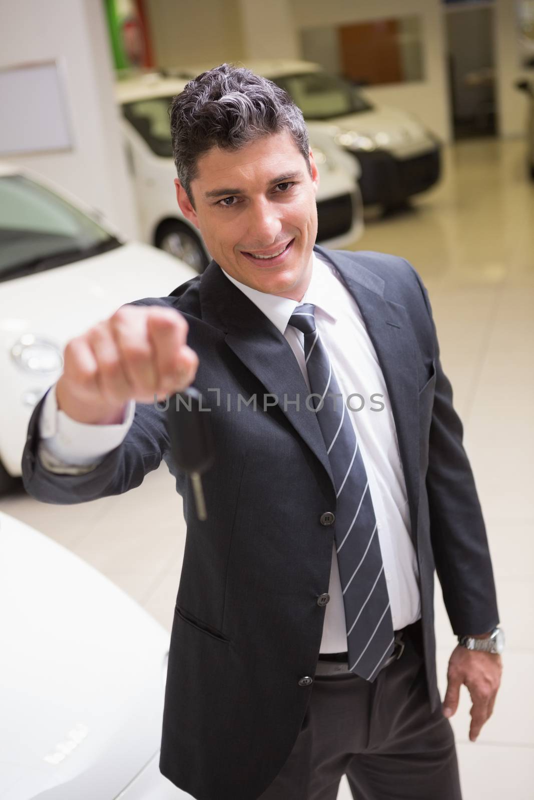 Salesman standing while offering car keys by Wavebreakmedia