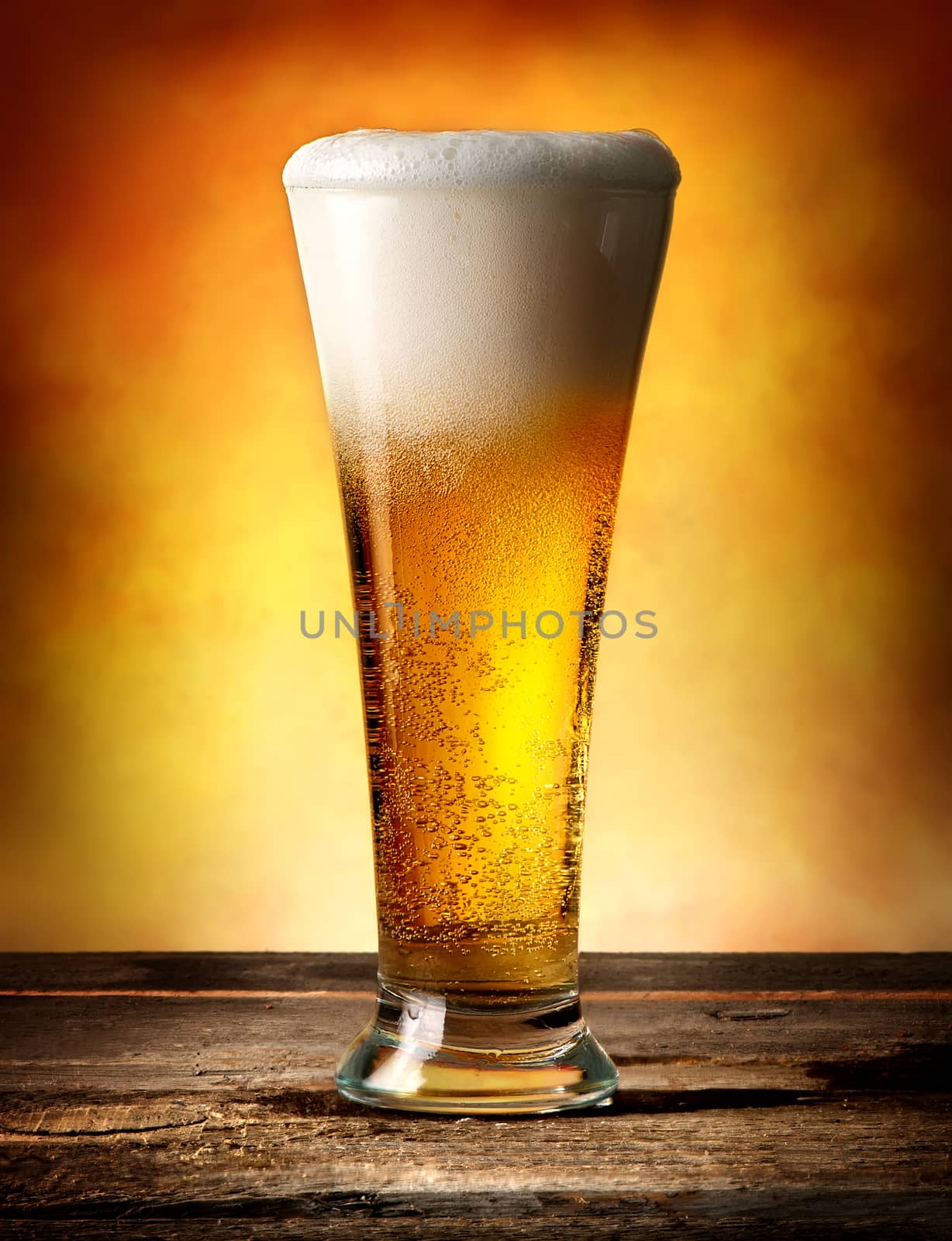 Glass of beer with bubbles on a wooden table