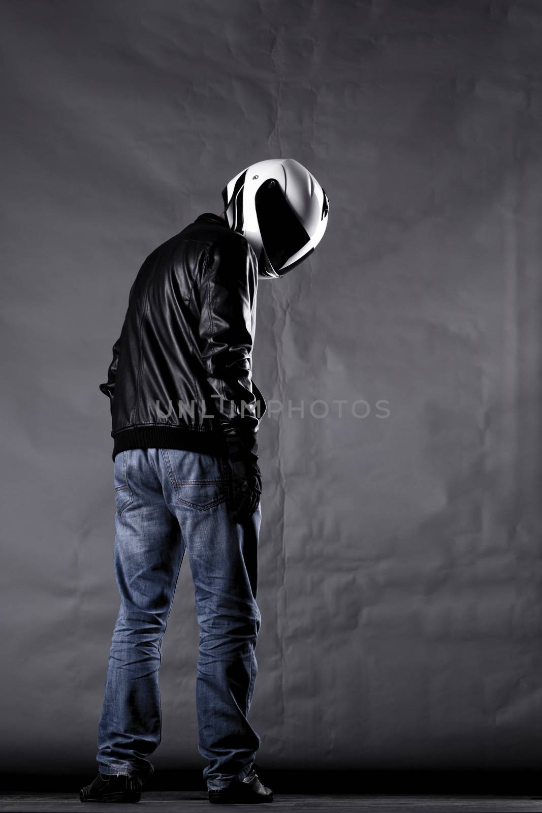 motorist with a helmet, leather jacket and jeans, on gray background