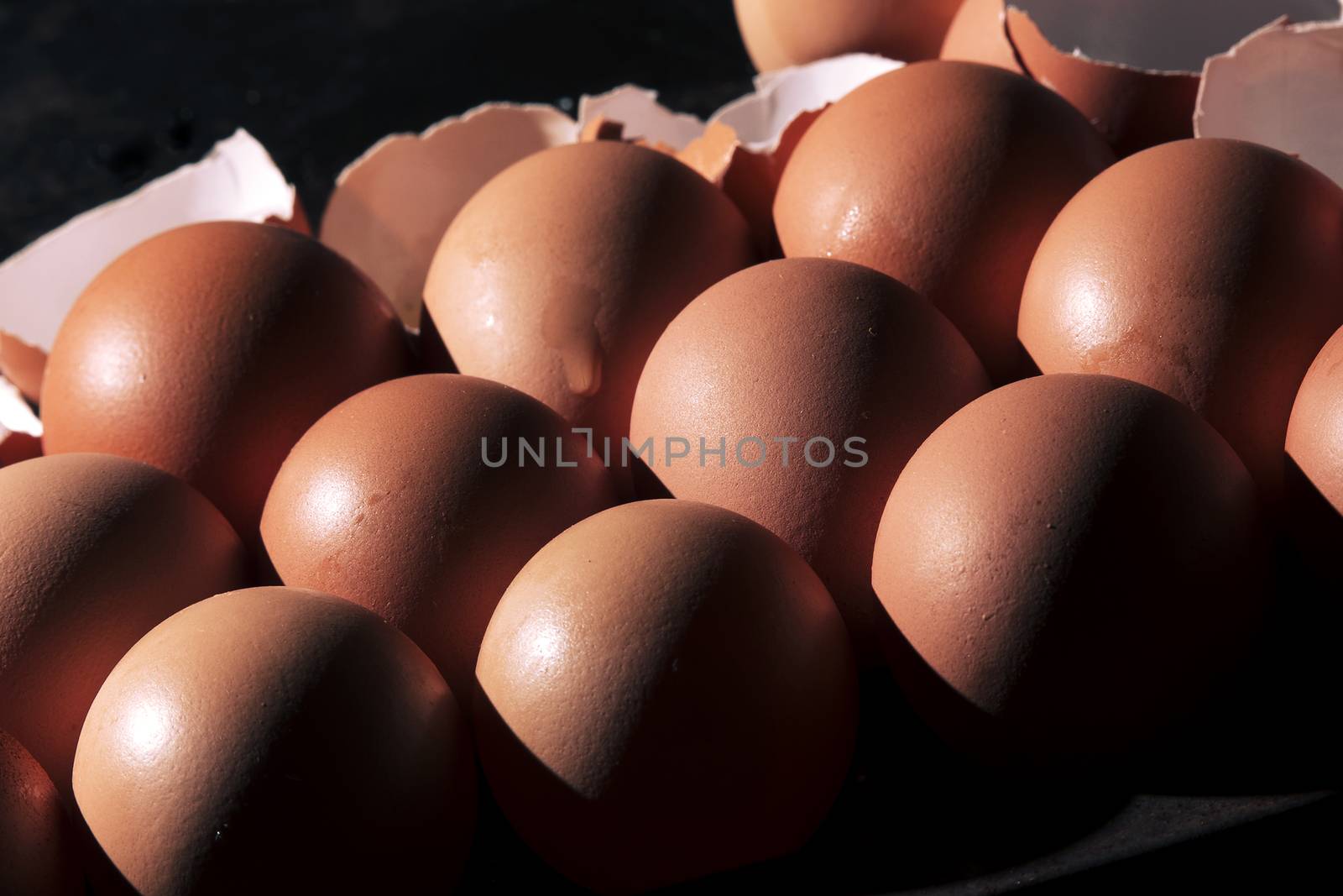 Low light with high contrast lighting of a bunch of eggs whole and crushed shells.