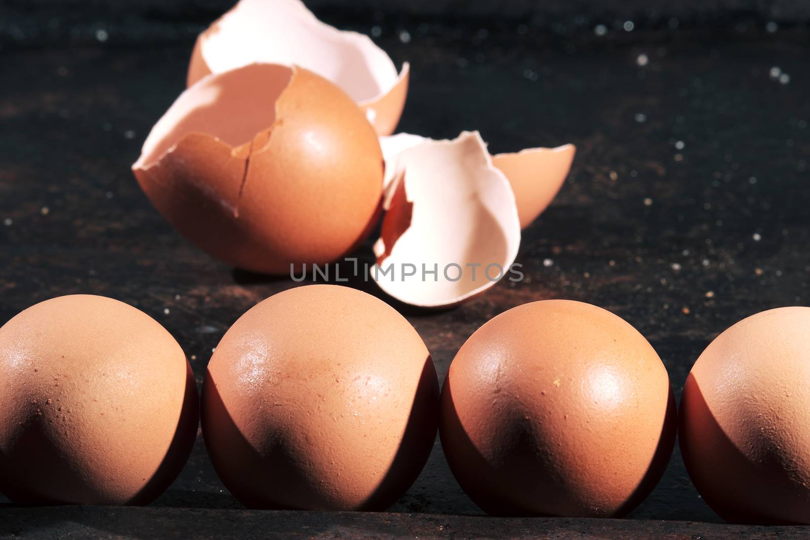 Low light with high contrast lighting of a bunch of eggs whole and crushed shells.