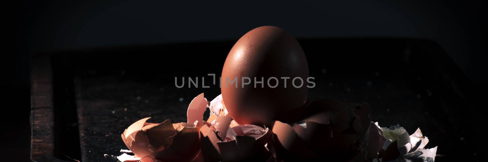 Low light with high contrast lighting of a bunch of eggs whole and crushed shells.
