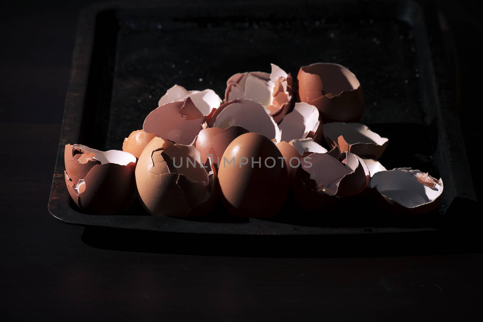 Low light with high contrast lighting of a bunch of eggs whole and crushed shells.