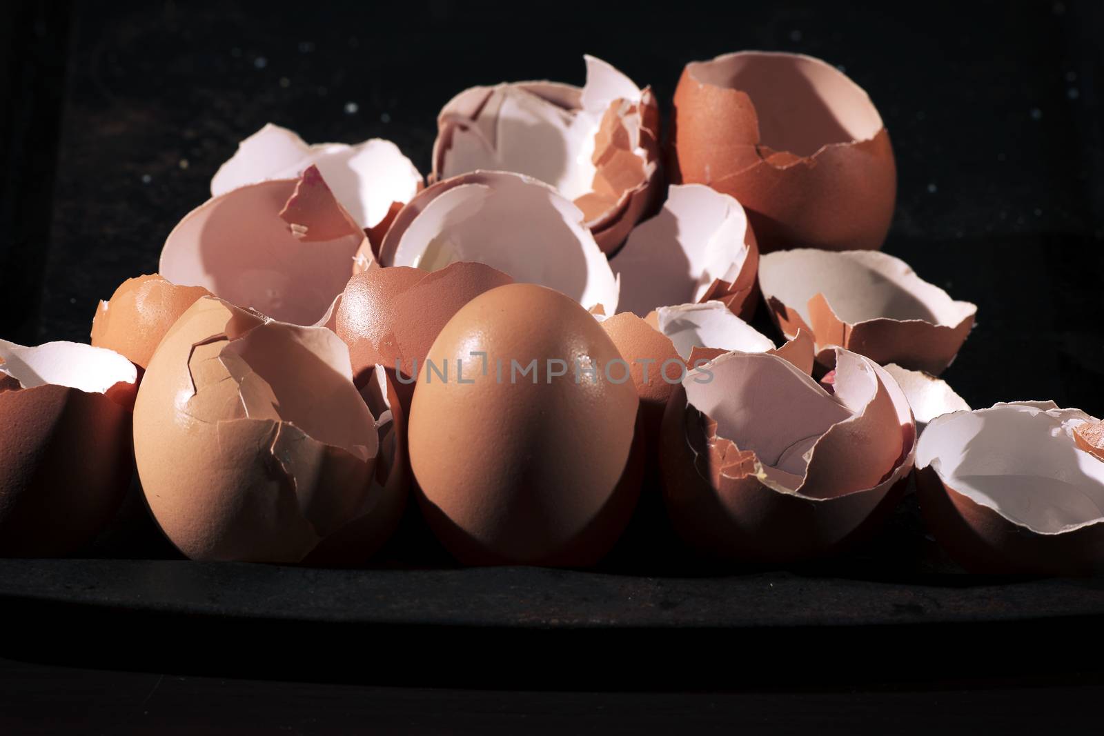 Low light with high contrast lighting of a bunch of eggs whole and crushed shells.