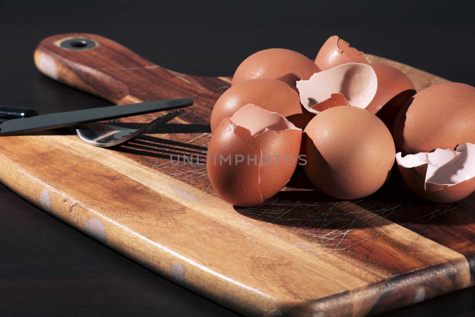 Low light with high contrast lighting of a bunch of eggs whole and crushed shells.