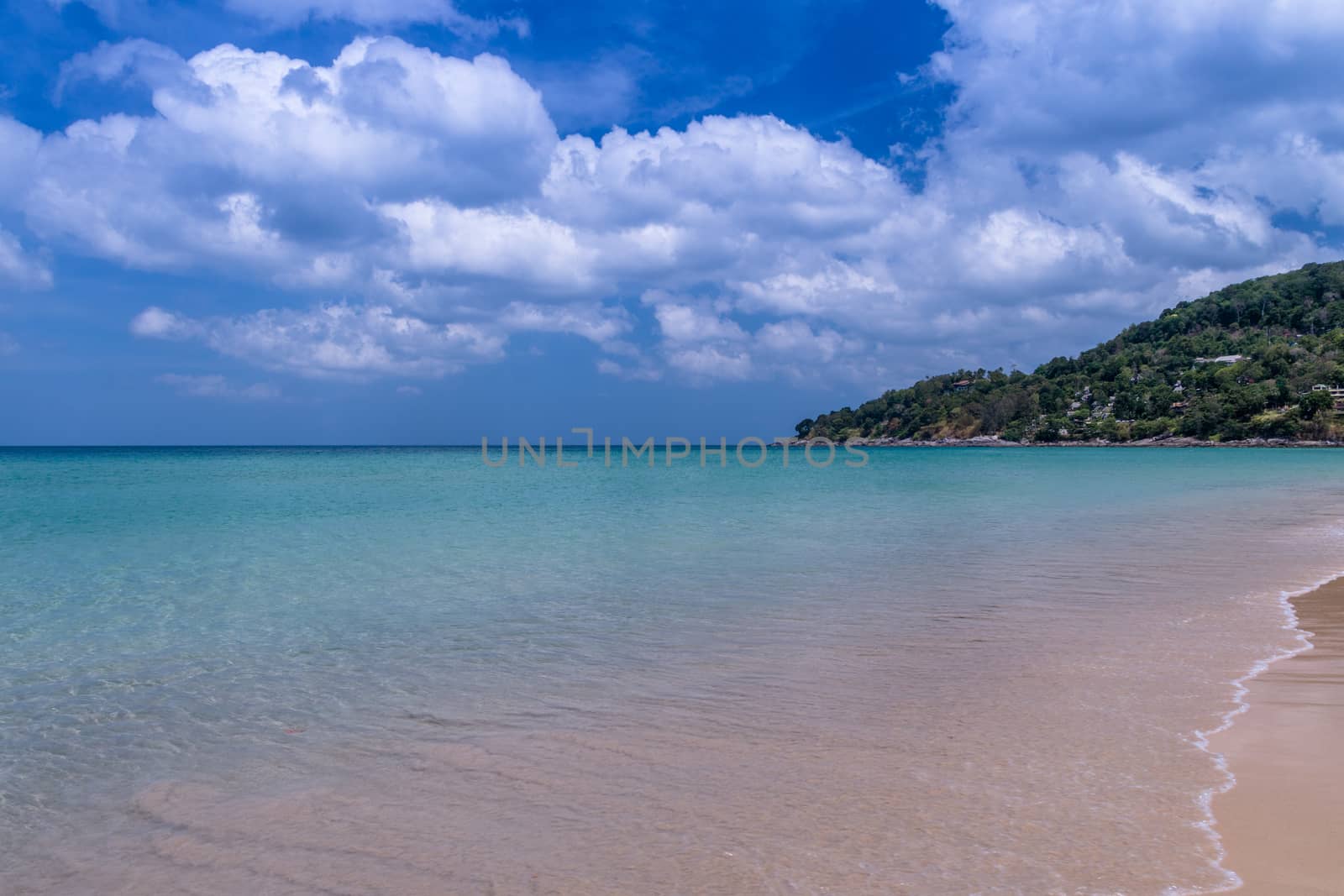 Sea beach with blue sky and yellow sand and some clouds above landscape