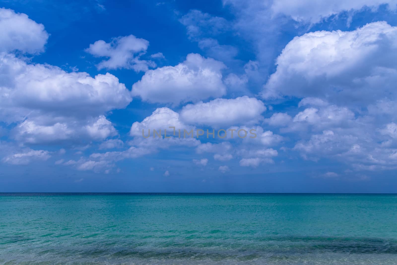 Sea beach with blue sky and yellow sand and some clouds above landscape