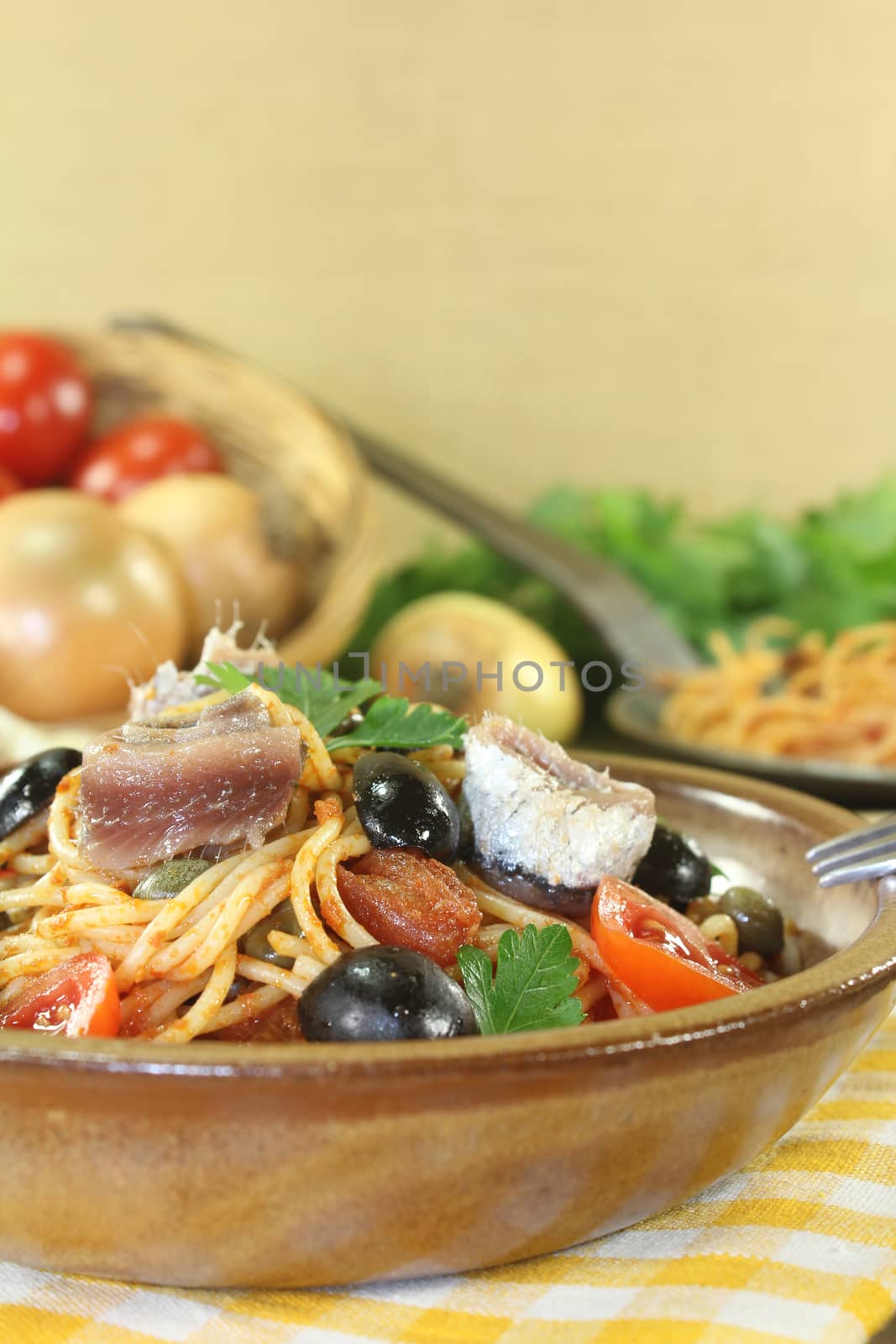 Spaghetti alla puttanesca with capers and anchovies on a napkin