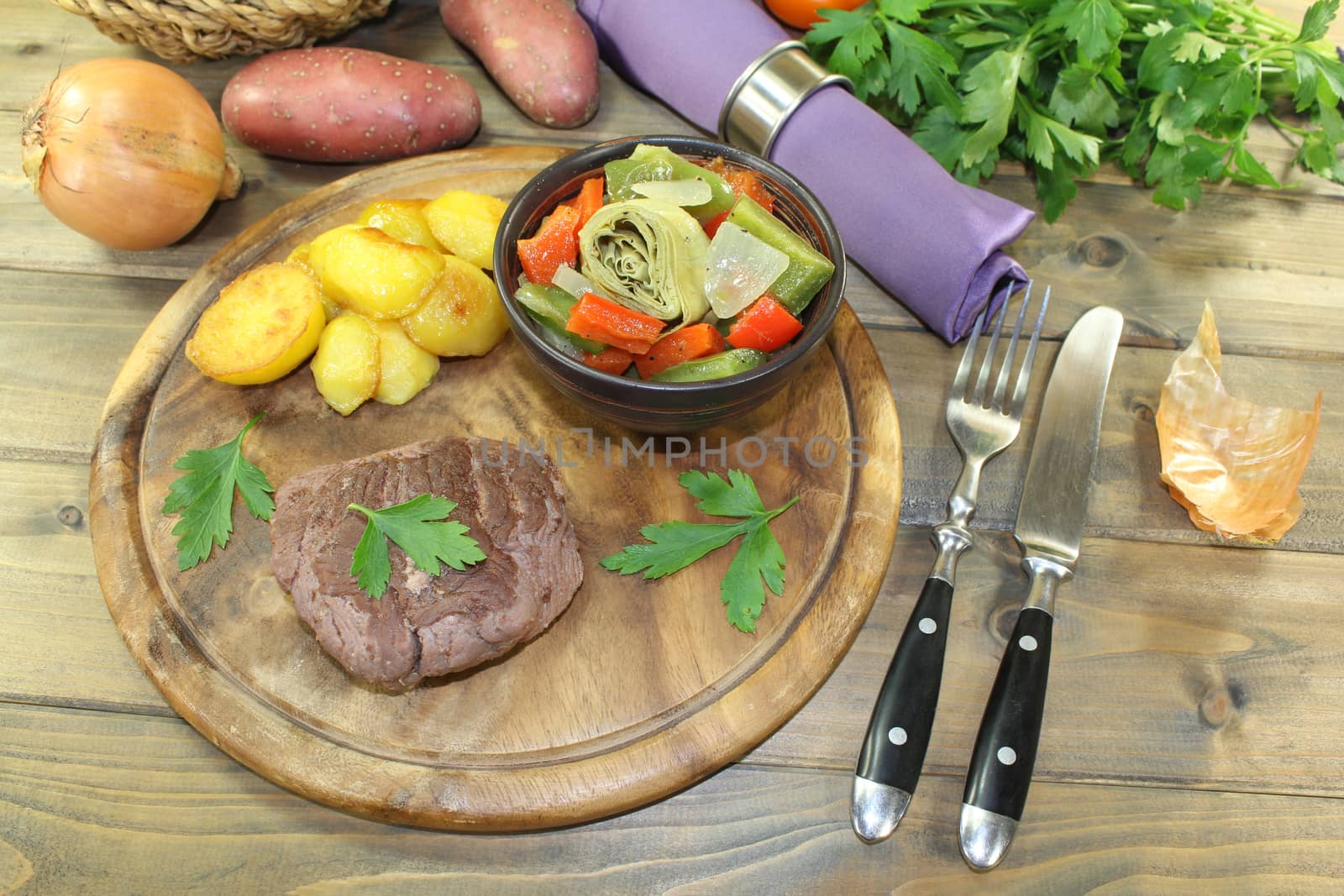 roasted ostrich steak with baked potatoes on a wooden board