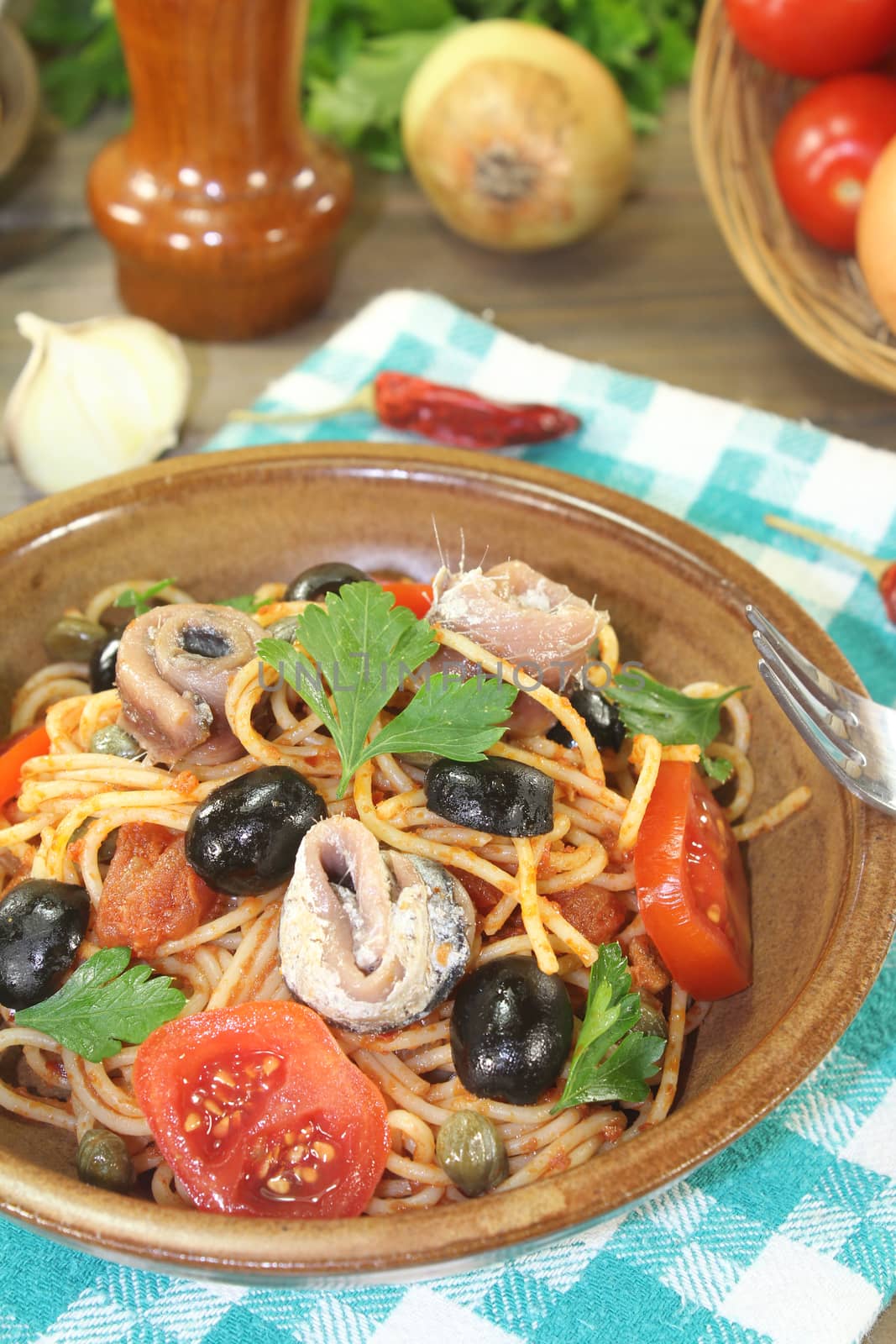 Spaghetti alla puttanesca with olives and anchovies on a napkin