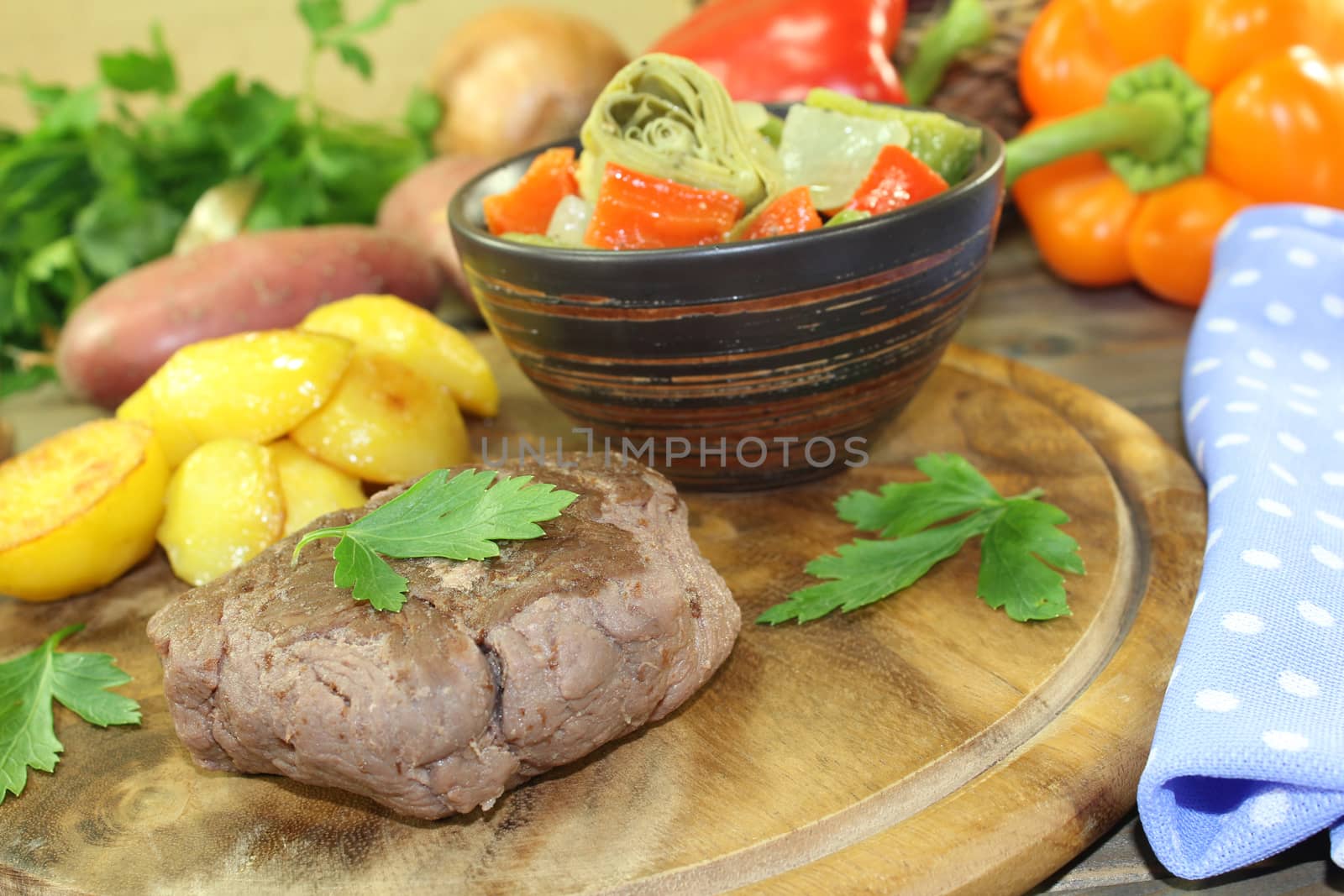 Ostrich steaks with baked potatoes and parsley on a wooden board