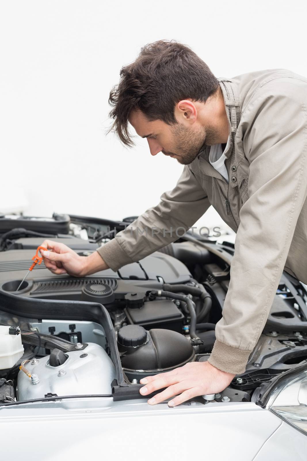 Man using dipstick to check oil by Wavebreakmedia