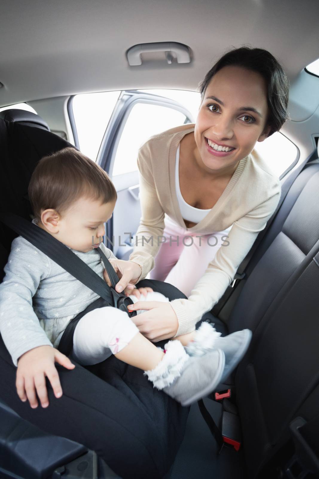 Mother securing her baby in the car seat in her car