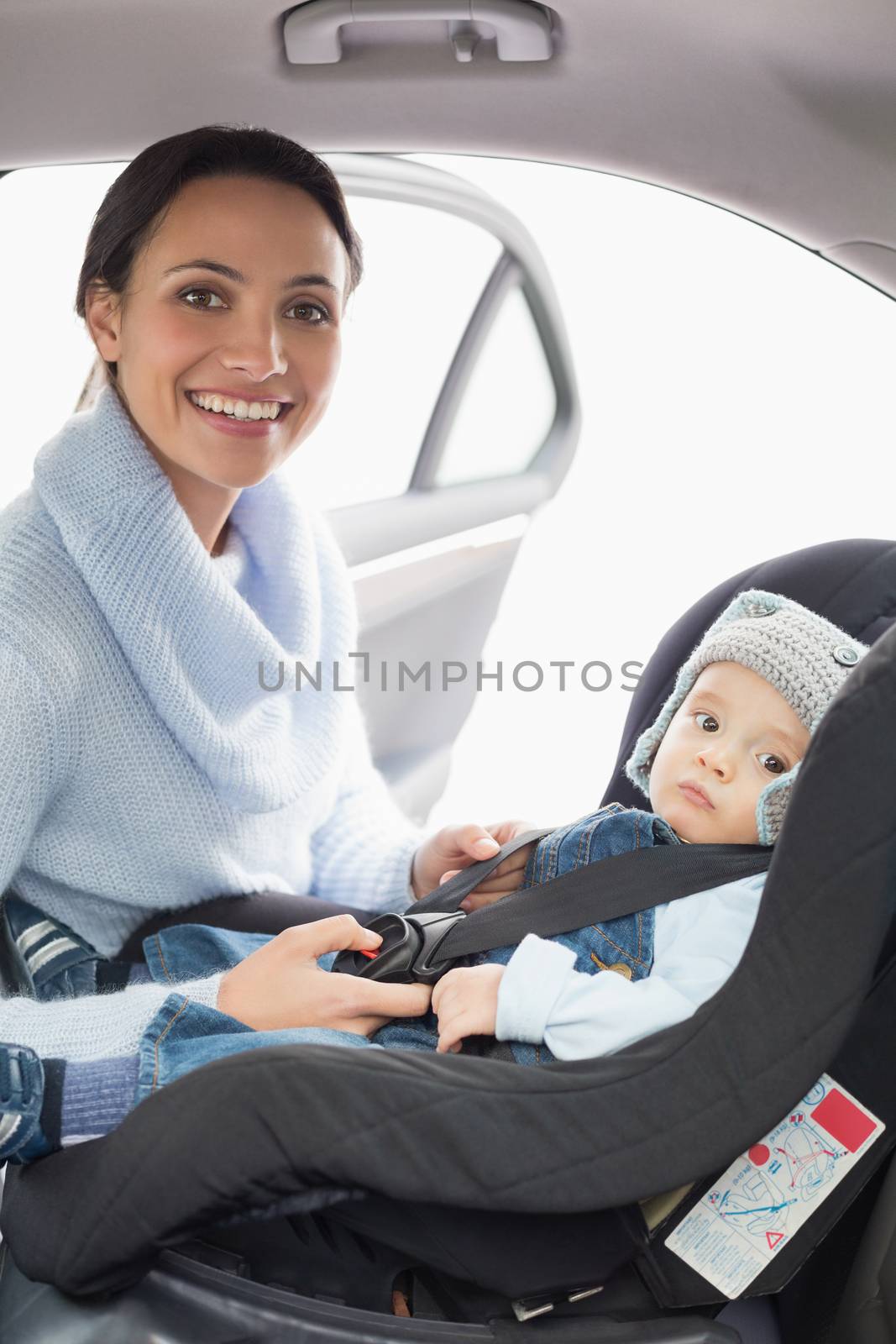 Mother securing her baby in the car seat in her car