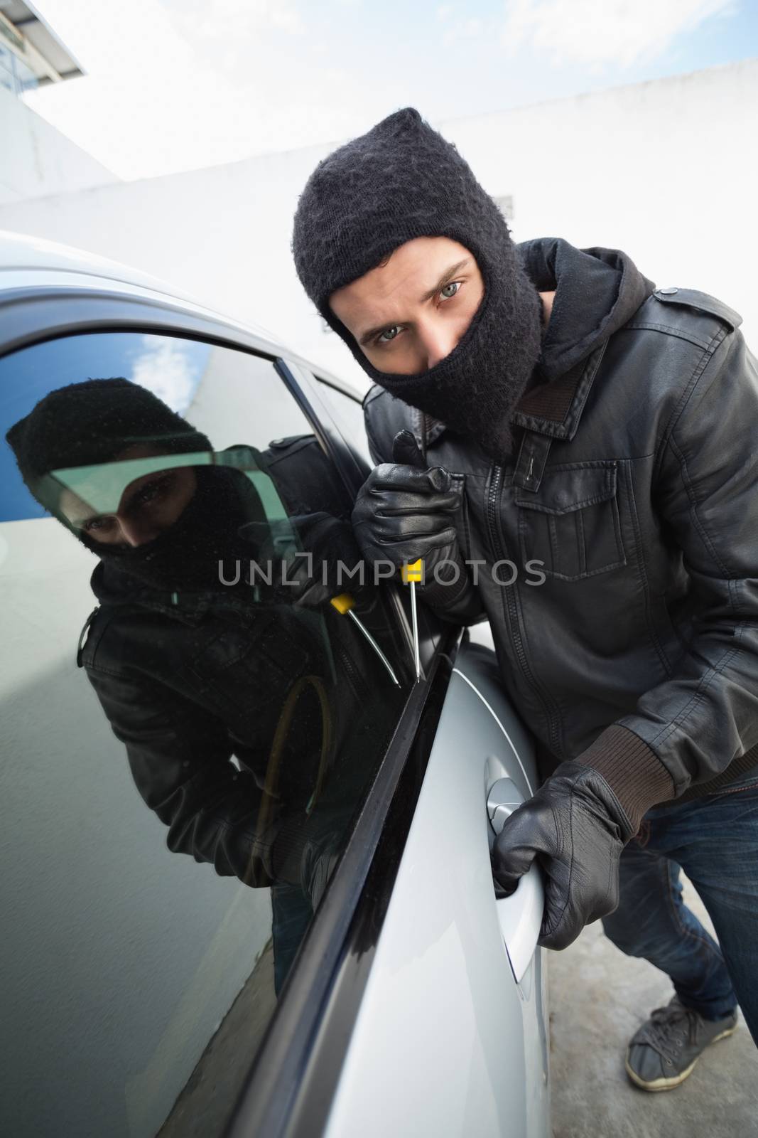 Thief breaking into a car in broad daylight