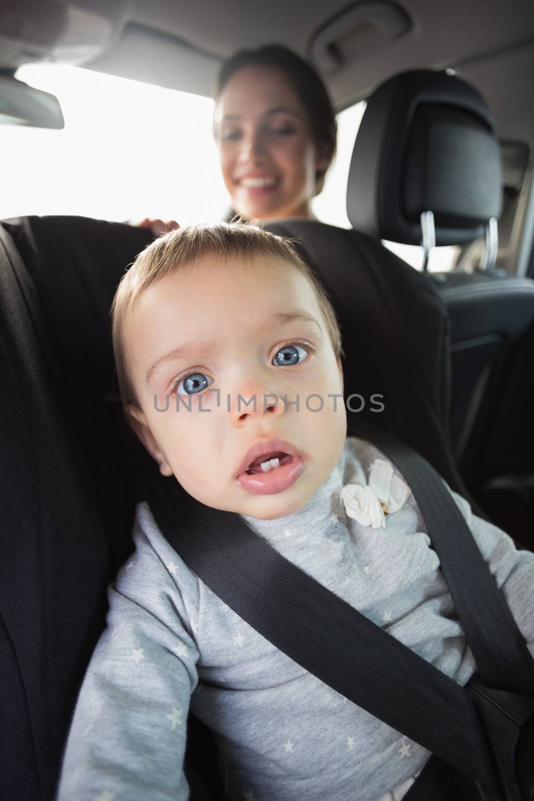 Mother checking her baby in the car seat in her car