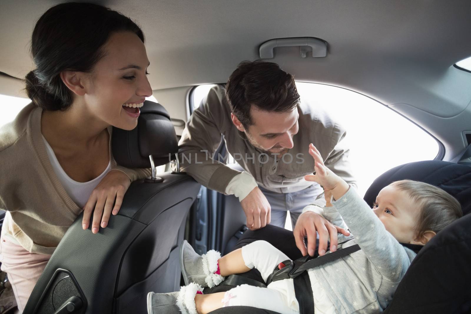Parents securing baby in the car seat in their car