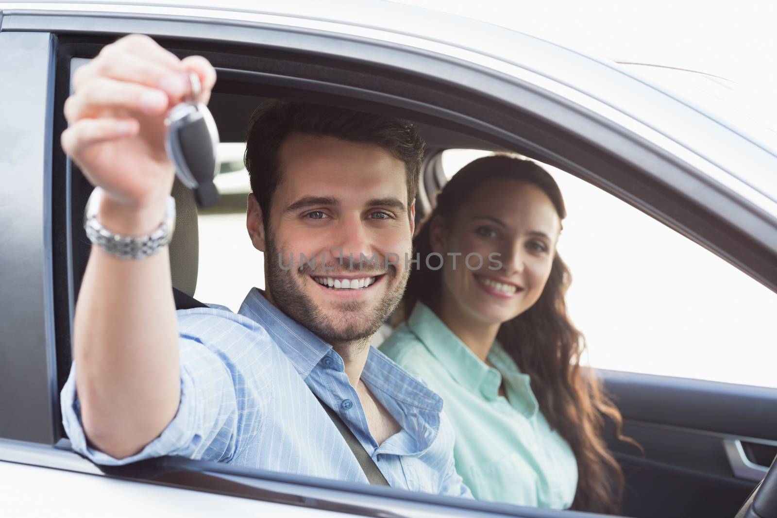 Young couple smiling at the camera in their car